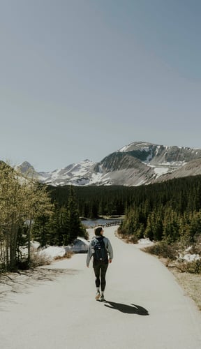 Hiker walking a trail toward snowy Rocky Mountain peaks near Fraser, Colorado